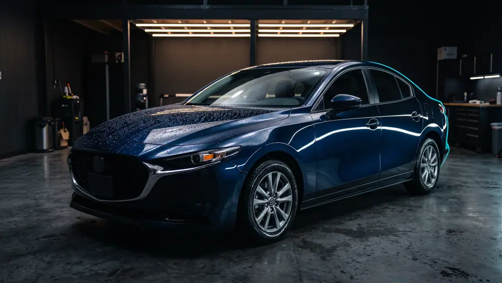A freshly detailed dark blue car with a deep mirror finish reflecting overhead lights.